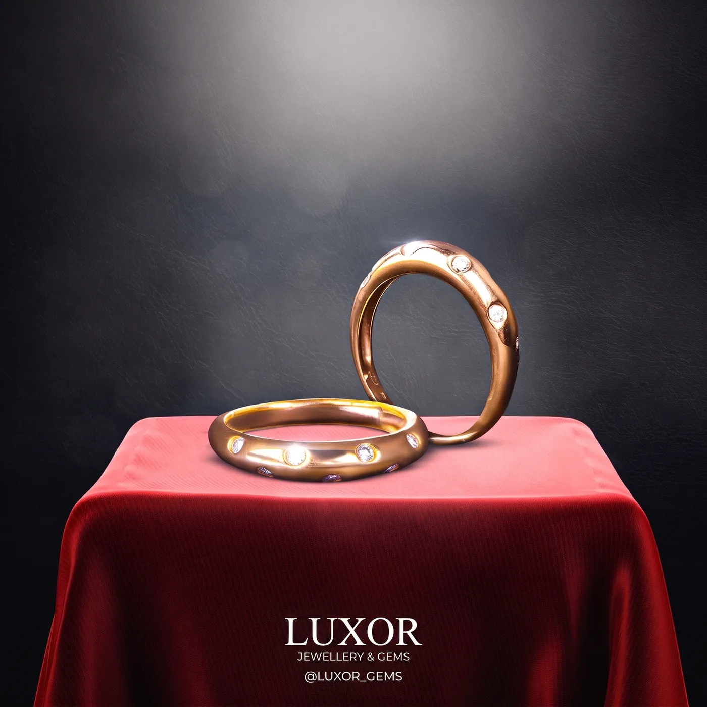 A finished jewellery post from our gallery: two gold rings set with small stones on a red cloth, with the jeweller's name underneath
